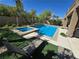 Beautiful pool and spa with lush landscaping and lounge chairs in a private backyard oasis at 8303 Saddleback Ledge Ave, Las Vegas, NV 89147