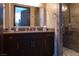 Modern bathroom featuring a dark vanity, large mirror, and tiled shower with glass door at 1123 Christian Rd, Henderson, NV 89002