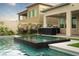 Backyard with black spa, pool, outdoor BBQ island and lush landscaping with egg-shaped chairs at 11990 Montague St, Las Vegas, NV 89138