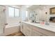 Bright bathroom with double sink vanity, bathtub with tile surround, and glass-enclosed shower at 12356 Notch Trail Ave, Las Vegas, NV 89138