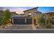 Contemporary home exterior features a three-car garage, desert landscaping and solar panels at 12356 Notch Trail Ave, Las Vegas, NV 89138