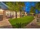Spacious backyard featuring a covered patio, stone columns, a lush green lawn, and desert landscaping at 2800 Proust Ct, Henderson, NV 89044