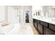 Well-lit bathroom with separate tub, shower, dual sinks, dark cabinets and walk-in closet at 7119 Saddle Back Peak St, Las Vegas, NV 89166