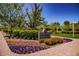 Well-maintained community entrance with colorful flowerbeds, mature trees, and signage for The Promenade at Providence at 7119 Saddle Back Peak St, Las Vegas, NV 89166