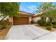 Home with large driveway, two-car garage, desert landscaping with shrubs and trees at 1172 Via Della Costrella, Henderson, NV 89011