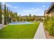 Sprawling backyard with a vibrant blue basketball court, lush green lawn, and manicured landscaping at 12119 Castilla Rain Ave, Las Vegas, NV 89138