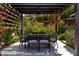 Outdoor dining area featuring a pergola with a ceiling fan and a dining table with seating for eight, surrounded by lush landscaping at 12119 Castilla Rain Ave, Las Vegas, NV 89138
