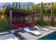 Beautiful pool area with a covered cabana, comfortable seating, and lush landscaping creating a private and relaxing retreat at 12119 Castilla Rain Ave, Las Vegas, NV 89138