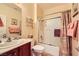 Well-lit bathroom features a shower-tub combo with neutral colors and dark wood vanity at 2213 Carrier Dove Way, North Las Vegas, NV 89084