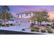 Beautiful two-story home with a three-car garage and mature landscaping at dusk at 2236 Timber Rose Dr, Las Vegas, NV 89134