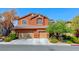 Two-story home featuring a three-car garage, terracotta color scheme, desert landscaping and a blue sky at 2733 Auchmull St, Henderson, NV 89044