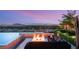 Backyard with a fire pit, built in seating and pool with lush greenery overlooks the city skyline at 34 Olympia Outlook Dr, Las Vegas, NV 89141