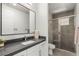 Modern bathroom featuring a dark countertop, white cabinets, large mirror, and a glass-enclosed shower with tiled walls at 34 Olympia Outlook Dr, Las Vegas, NV 89141