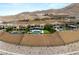 An elevated view of a lavish estate featuring multiple homes with pools, elegant landscaping, and desert hillside backdrop at 34 Olympia Outlook Dr, Las Vegas, NV 89141
