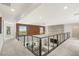 Spacious hallway overlooking the living room with modern railing and stylish wood and concrete accent walls at 34 Olympia Outlook Dr, Las Vegas, NV 89141