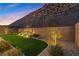 Backyard at dusk showcasing artificial turf, rock landscaping, and privacy fence at 461 Cascade Heights Ave, Las Vegas, NV 89138