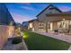 A well-lit backyard featuring a covered patio, manicured landscaping, and lush green turf at 461 Cascade Heights Ave, Las Vegas, NV 89138