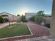 Backyard featuring desert landscaping, including rocks, shrubs, and a small patch of lawn at 4837 Skyraider St, North Las Vegas, NV 89031