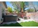 Backyard featuring a fire pit, mature landscaping, artificial turf, hardscape patio, and a hot tub at 5000 Charlo Dr, Las Vegas, NV 89131