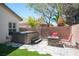 Backyard featuring a fire pit, mature landscaping, artificial turf, hardscape patio, and a hot tub at 5000 Charlo Dr, Las Vegas, NV 89131