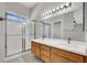Bathroom featuring a double sink vanity, framed mirror, walk-in shower, and modern lighting at 5244 Velazco Ln, Las Vegas, NV 89130