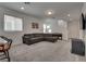 Spacious living room with carpet, a large grey sofa, and staircase access at 5256 Sherwood Forest Ln, Las Vegas, NV 89122