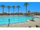 Sparkling community pool surrounded by lounge chairs and palm trees under a clear blue sky at 6072 Canter Glen Ave, Las Vegas, NV 89122