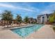 Community pool with trees, lounge chairs, handrails, and nearby housing at 6148 Juniper Grove St, Las Vegas, NV 89148