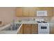 Cozy kitchen featuring light wooden cabinets, white appliances and stainless steel sink at 6217 Lapilli Ave, Las Vegas, NV 89139