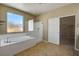 Bathroom showcasing a large soaking tub, glass shower, tile flooring, and a walk-in closet at 6442 American Eagle Ave, Las Vegas, NV 89131