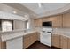 Well-lit kitchen features tile counters, white appliances, wood cabinets, and a seamless cutout to another room at 7950 W Flamingo Rd # 2019, Las Vegas, NV 89147