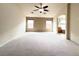 Spacious carpeted main bedroom featuring a ceiling fan, two windows, and an archway leading to the ensuite bathroom at 8161 Cane Creek Mill Ct, Las Vegas, NV 89131