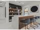 Modern home bar with white countertop, wood accents, bar stools and sleek shelving at 82 Glade Hollow Dr, Las Vegas, NV 89135