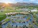 Stunning aerial view of a golf course clubhouse surrounded by lush greens, mature trees, and ample parking at 82 Glade Hollow Dr, Las Vegas, NV 89135