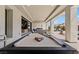 Covered outdoor living space with a pool table, fireplace and lounge seating with desert views at 82 Glade Hollow Dr, Las Vegas, NV 89135