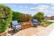 Cozy backyard seating area with a modern fire pit, surrounded by lush greenery and blue skies at 9588 Vital Crest St, Las Vegas, NV 89123