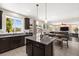 Open-concept kitchen with island, dark cabinets, and view into the dining area and living room at 9588 Vital Crest St, Las Vegas, NV 89123