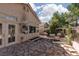 Wide view of the exterior home and a stone patio, garden beds and mature landscaping at 1709 Pacific Panorama Pl, Las Vegas, NV 89144