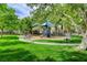 Community playground with swings, slides, and benches surrounded by green grass and shady trees at 2338 Dolphin Ct, Henderson, NV 89074