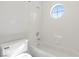 White tiled bathroom with bathtub and bright, round window at 283 Grand Olympia Dr, Henderson, NV 89012