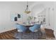 Chic dining area features a round table, blue chairs, modern chandelier, and wood-look floors at 283 Grand Olympia Dr, Henderson, NV 89012