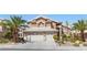 Two-story home with a two-car garage, desert landscaping, and palm trees at 283 Grand Olympia Dr, Henderson, NV 89012