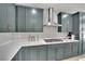 Stylish kitchen featuring stainless steel appliances, sleek quartz countertops, and modern light-green cabinetry at 10038 W Meranto Ave, Las Vegas, NV 89178