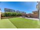 Artificial turf, shrubbery, and neighboring houses provide a relaxing backyard view at 10042 Bismuth St, Las Vegas, NV 89183