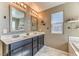 Bright bathroom featuring a double sink vanity, large mirrors, and a window for natural light at 10042 Bismuth St, Las Vegas, NV 89183