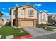 Tan two-story home with a two-car garage, stone accents, and a well-manicured lawn on a sunny day at 1618 Meno Peak St, Las Vegas, NV 89115