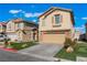 A tan two-story home with stone accents on the garage and porch with manicured front lawn at 1618 Meno Peak St, Las Vegas, NV 89115