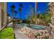 Serene backyard featuring a rock-rimmed hot tub, swimming pool, and a tiki hut with lush landscaping at 1994 Orchard Mist St, Las Vegas, NV 89135
