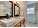 Elegant bathroom featuring double sinks with modern fixtures, framed mirrors, and a view of the shower at 2246 Almart Cir, Henderson, NV 89014
