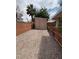 Gravel backyard with a wooden shed, red brick fence, and tropical landscaping at 228 Hiawatha Way, Mesquite, NV 89027